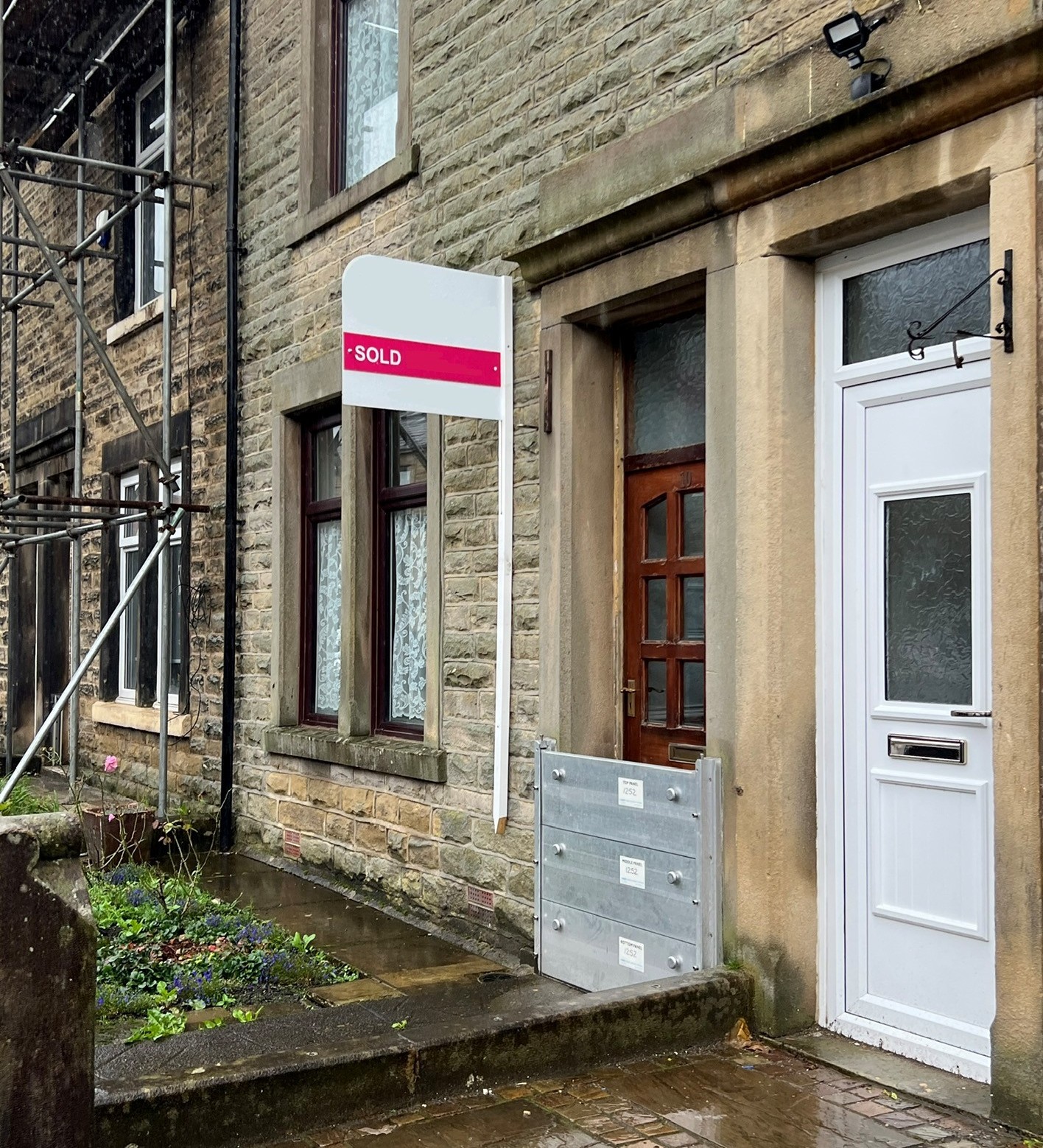 A house with a for sale sign up and flood barriers deployed. 
